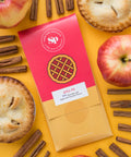 Nostalgic Apple Pie Chocolate Bar with fresh apples, cinnamon sticks, and mini pies on a vibrant yellow background.
