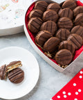 Heart-shaped box with milk chocolate-covered peanut butter cracker cookies and a red polka dot napkin.