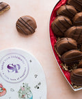 Heart-shaped box of handcrafted milk chocolate-covered peanut butter crackers from Sugar Plum, presented on a light background.