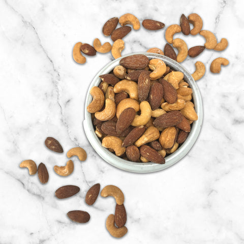 Premium salted cashews and almonds in a white bowl on a marble surface, showcasing Damn Man Black Label's refined nut selection.