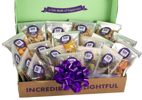 Large snack box filled with assorted treats, featuring a purple ribbon and labeled "a little taste of happiness" inside lid.