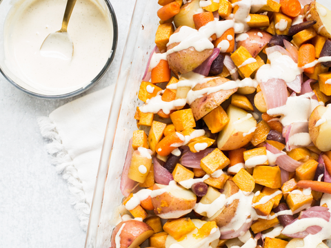 Roasted vegetables with creamy sauce featuring potatoes, carrots, and onions in a baking dish, perfect for a zesty horseradish seasoning.